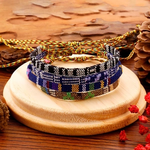 Detailopname van geweven bohemian armbanden met diverse patronen op natuurlijk hout