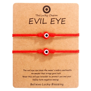 Detail von zwei handgemachten roten Evil-Eye-Armbändern auf brauner Papierkarte