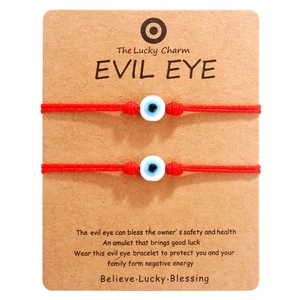 Detaillierte Ansicht von zwei roten Evil Eye Armbändern auf brauner Karte mit Beschreibung