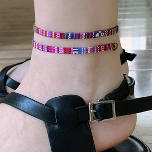 Detailweergave van bohemien kleurrijke gevlochten enkelbandjes om de enkel