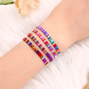 Detailopname van vier kleurrijke bohemian gevlochten armbanden met etnische patronen