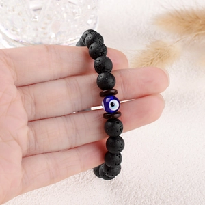 8mm black lava stone bead bracelet featuring evil eye charm worn on a female wrist