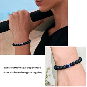 Detailed close-up of 8mm black lava stone beads and blue evil eye charm on a stretch bracelet