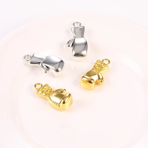 Golden and silver boxing glove metal pendants for DIY jewelry making on a white tray