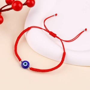 Detail of red braided evil eye bracelet with adjustable sliding knot and blue bead