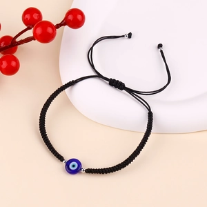 Detailed close-up of handmade black woven bracelet featuring a blue evil eye bead and silver spacers
