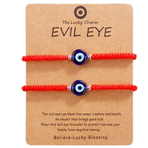 Set of two red woven evil eye bracelets with blue glass beads on card display