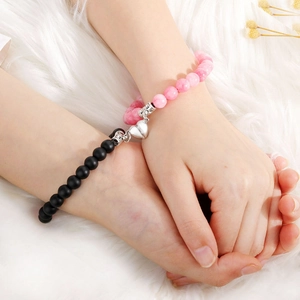 Pink and black beaded magnetic heart couple bracelets on a soft white fur background