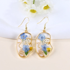 Macro detail of abstract face earrings with resin-embedded colorful dried flowers