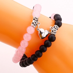 Detail der Magnet-Herz-Anhänger an Armbändern aus rosa Kristall und schwarzem Naturstein