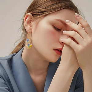 Close-up of model wearing irregular gold resin earrings with embedded real dried flowers
