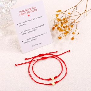Detail of red string bracelets with heart charms on a meaningful gift card