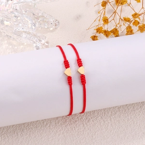 Detailed view of red woven couple bracelets with heart pendants on display stand