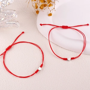 Detailed view of adjustable red woven bracelets with polished silver heart charms
