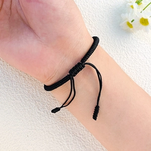 Detail eines handgewebten schwarzen Kordelarmbands mit verstellbarem Knoten am Handgelenk