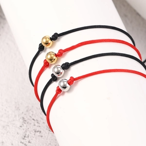 Detail of red and black braided cord bracelets with polished gold and silver beads