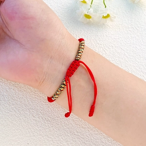 Makroaufnahme eines handgeflochtenen roten Seilarmbands mit bunten Knoten an der Hand