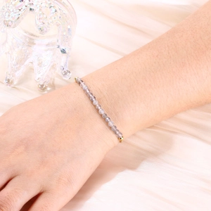 Detailed shot of labradorite beaded bracelet with gold accents on a silk fabric background