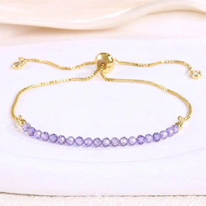 Detail view of gold adjustable slider bracelet with purple faceted crystals and charms