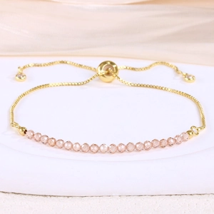 Detail of adjustable gold chain bracelet with faceted pink crystal beads on white stand