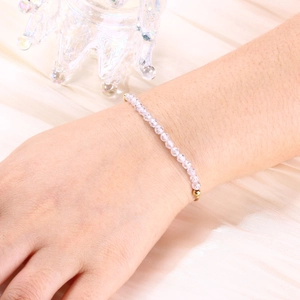 Detail of a 4mm pink crystal beaded bracelet with gold plated accents on satin