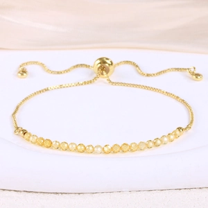 Detail of adjustable gold box chain bracelet with yellow faceted crystal beads