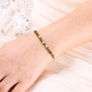 Detail of 4mm faceted natural stone beads on a gold-plated bracelet worn on a wrist