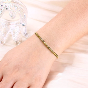 Detailed macro view of an olive green faceted crystal bead bracelet on a silk background