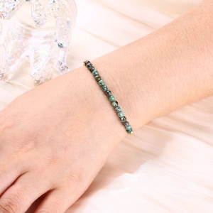 Detail of faceted green natural stone beaded bracelet on wrist with gold bead accents
