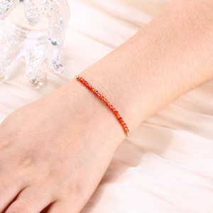 Detail of red faceted crystal beads and gold-plated clasp on delicate female bracelet