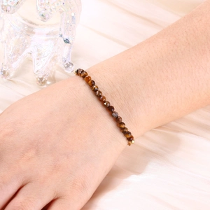 Detail of 4mm faceted tiger eye stone beads on a gold-plated bracelet worn on wrist