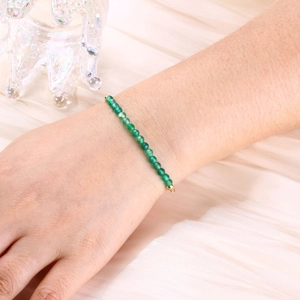 Detailed close-up of a 4mm faceted green crystal beaded bracelet with gold snake chain plating