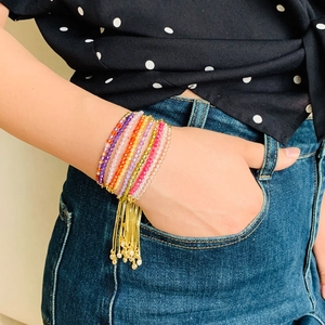Close-up of bohemian multi-layer colorful crystal bead bracelet with gold fringe tassel