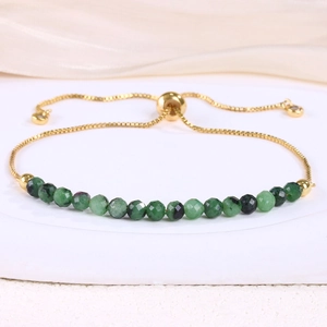 Detail of adjustable gold bolo bracelet with 18 green faceted crystal beads on a stone base