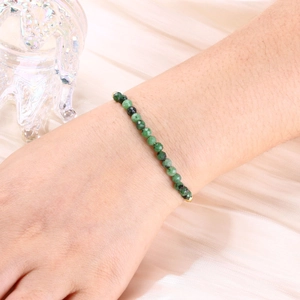 Detailed shot of a 4mm faceted green stone beaded bracelet on a soft satin background