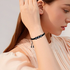 Detail of adjustable black woven bracelet with heart symbols and letter A bead on wrist
