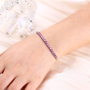 Detail of a purple faceted crystal bead bracelet with gold accents on a silk background
