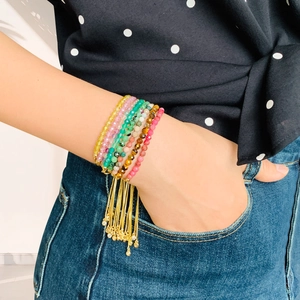 Detail of multi-layered crystal beaded bracelet set with gold tassels on female wrist