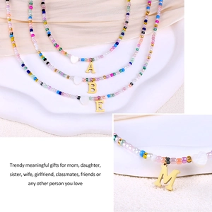 Macro shot of colorful seed bead necklace with gold initial M and heart charm detail