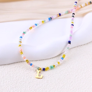 Dettaglio della collana di perline colorate con un ciondolo lucido dorato con la lettera L