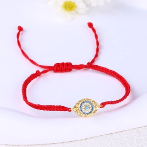 Detail of red woven bracelet with evil eye charm and blue zircon stones