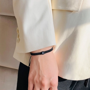 Κοντινό πλάνο μαύρου πλεκτού βραχιολιού με τετράγωνη χάντρα γράμμα Α στον καρπό
