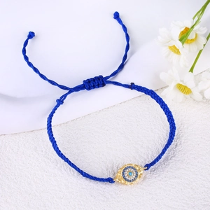 Detail of blue braided evil eye bracelet with gold plating and cubic zirconia stones
