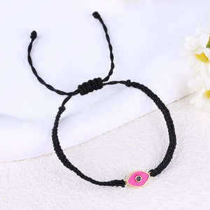 Detail of hand-woven black cord bracelet with a pink evil eye charm and gold accents