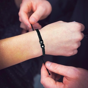 Pulsera tejida negra ajustable con la letra A y cuentas de corazón en escena de uso
