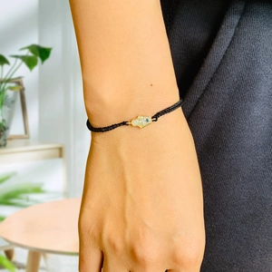 Detailed view of hand-woven black cord bracelet with Hamsa Hand and Evil Eye charm on wrist
