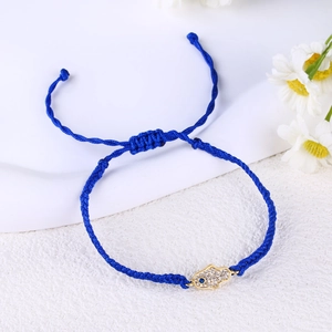 Detail of hand-woven blue cord bracelet with gold Hamsa Hand pendant and zircons