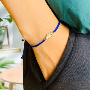 Detailed shot of Hamsa Hand charm with blue eye on woven navy cord bracelet