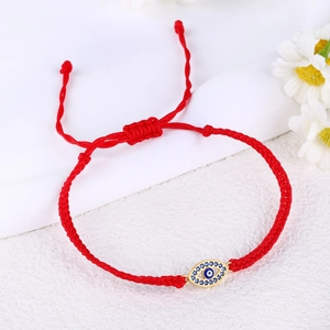 Detailed macro shot of a handmade red braided Evil Eye bracelet featuring blue zircon stones