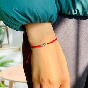 Close-up of a red woven Evil Eye bracelet with blue zircon and sparkling crystals